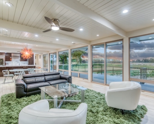 A cozy living room with a ceiling fan and a picturesque view of the golf course.