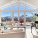 A cozy living room with a grand piano and large windows offering breathtaking views of the mountains.
