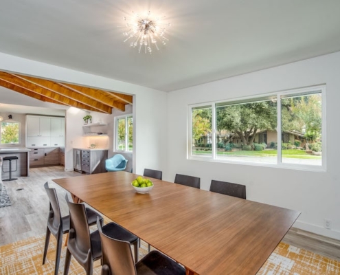 A well-lit dining room showcasing a wooden table surrounded by chairs, creating an inviting space for meals and gatherings.
