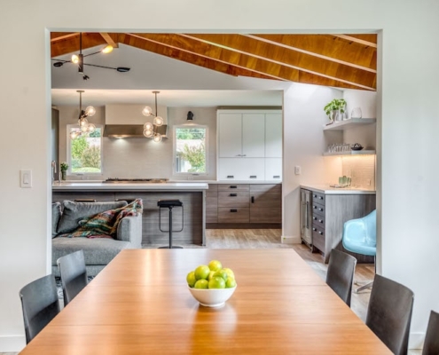 A cozy kitchen and dining room with a rustic wooden ceiling, creating a warm and inviting atmosphere.