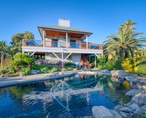 A house with a pool surrounded by palm trees on a sunny day.