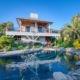 A house with a pool surrounded by palm trees on a sunny day.