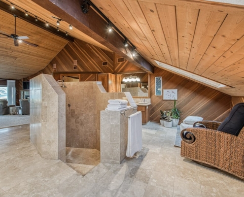 A bathroom with a shower and a wicker chair.