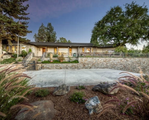 A house with a stone wall and well-maintained landscaping in front.