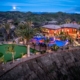 A large home with a pool and a golf course illuminated at night, creating a serene and luxurious atmosphere.