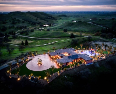 Aerial view of a spacious hilltop mansion surrounded by lush greenery.
