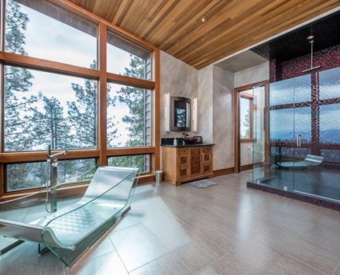 A spacious bathroom featuring a sizable glass shower and a generously sized window.