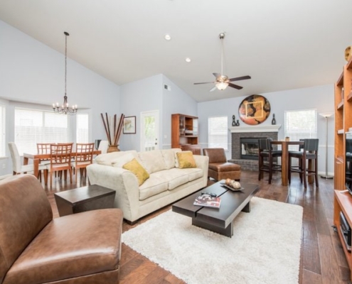 Spacious, well-lit living room with a dining area, high ceiling, and modern furnishings
