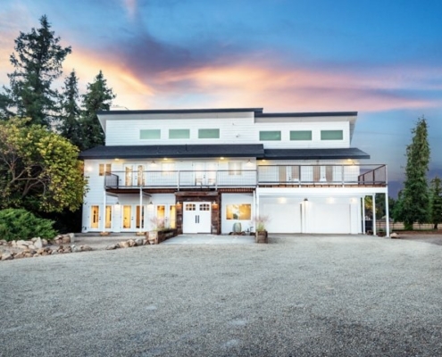 Photo of Modern two-story house at dusk with illuminated windows and a spacious driveway.