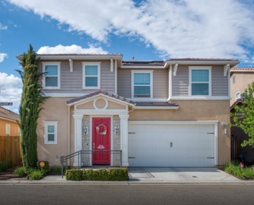 Photo of exterior front view of two story house and tall bushes by Rees Photography